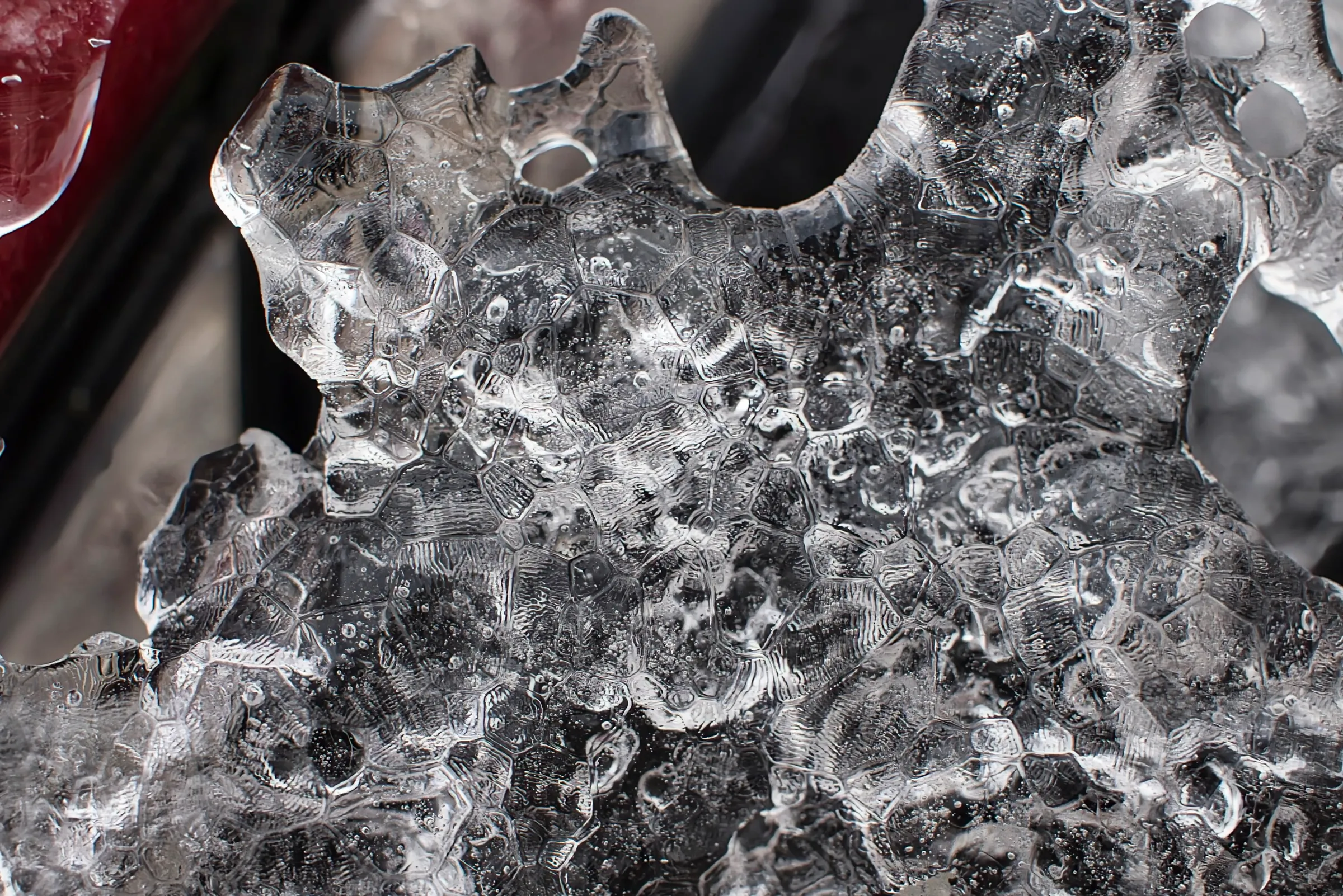 Macro photo of ice clinging to the window of a car after an ice storm. It has a very lumpy texture with polygonal shapes
